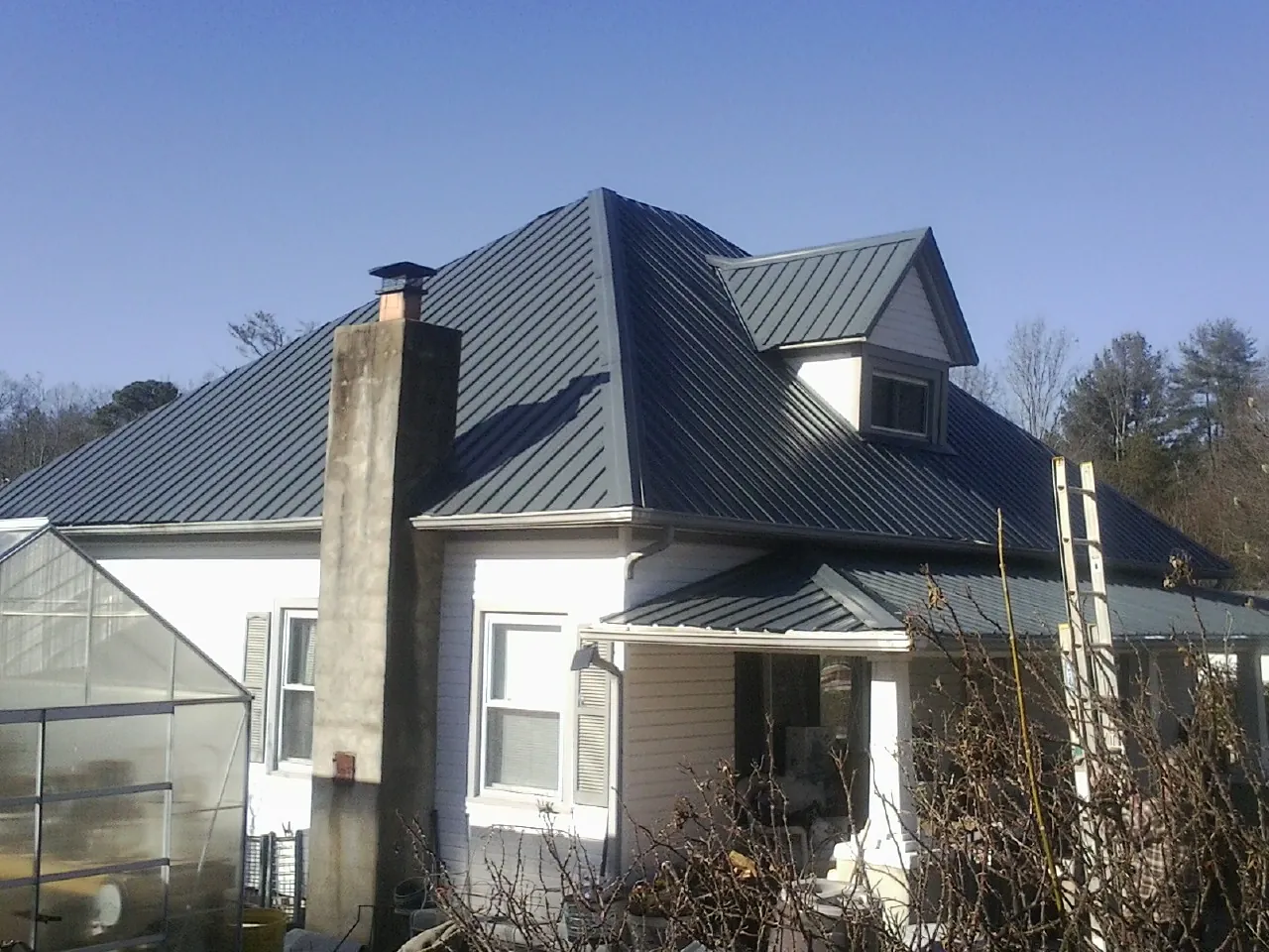 Dark blue standing seam metal roof on a white farmhouse with dormer — Slate & Tile Roof Repair by Roofing Brothers in Monongahela
