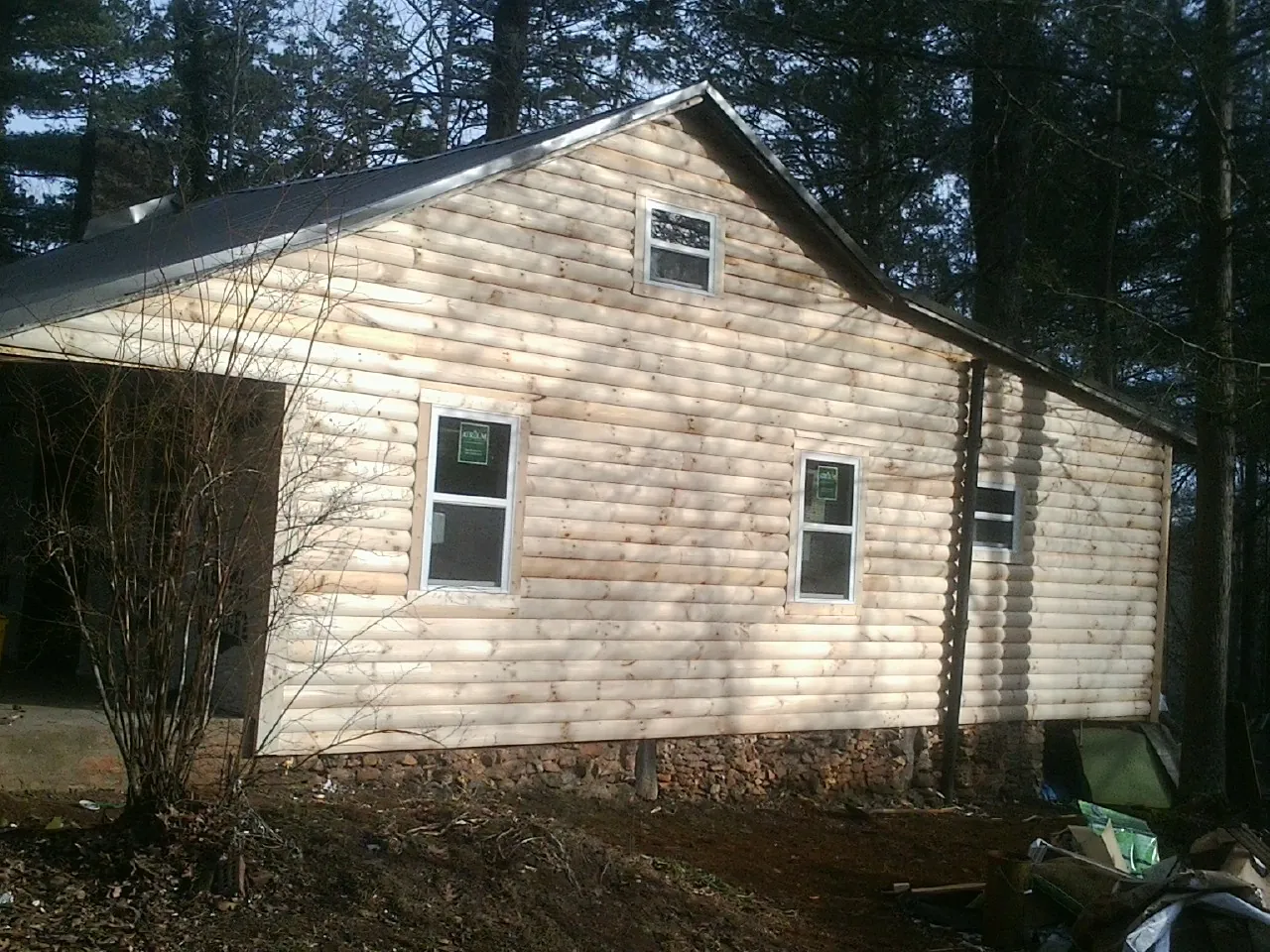 New log siding and dark metal roofing on a gable end in Monongahela