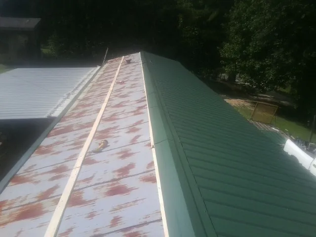 Old rusted panels beside newly installed green metal roofing — Wind Damage Roof Repair by Roofing Brothers in Monongahela
