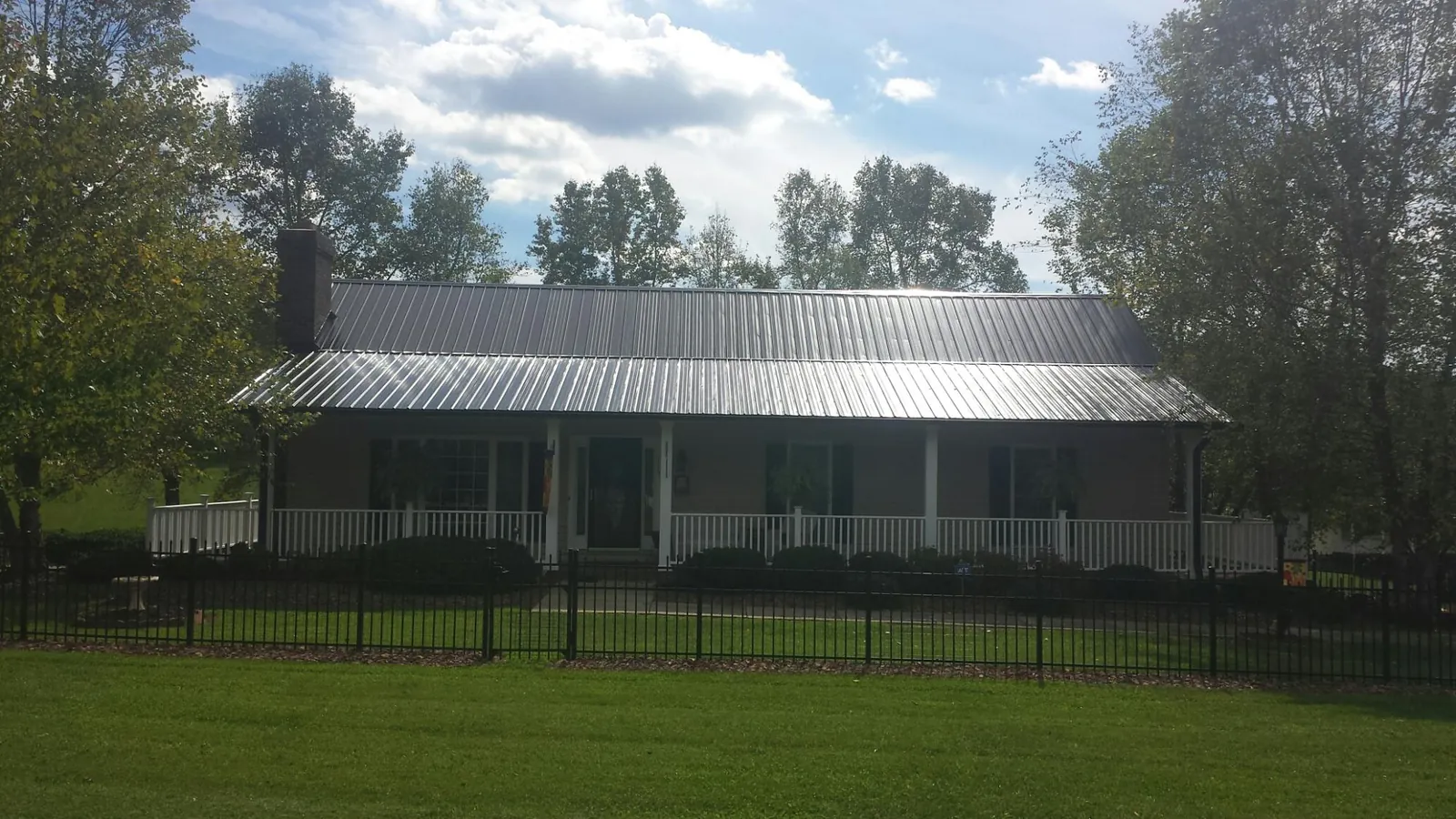 Gray metal roof on a brick ranch with a full width front porch — Gutter Guard Installation work by our crew in Monongahela