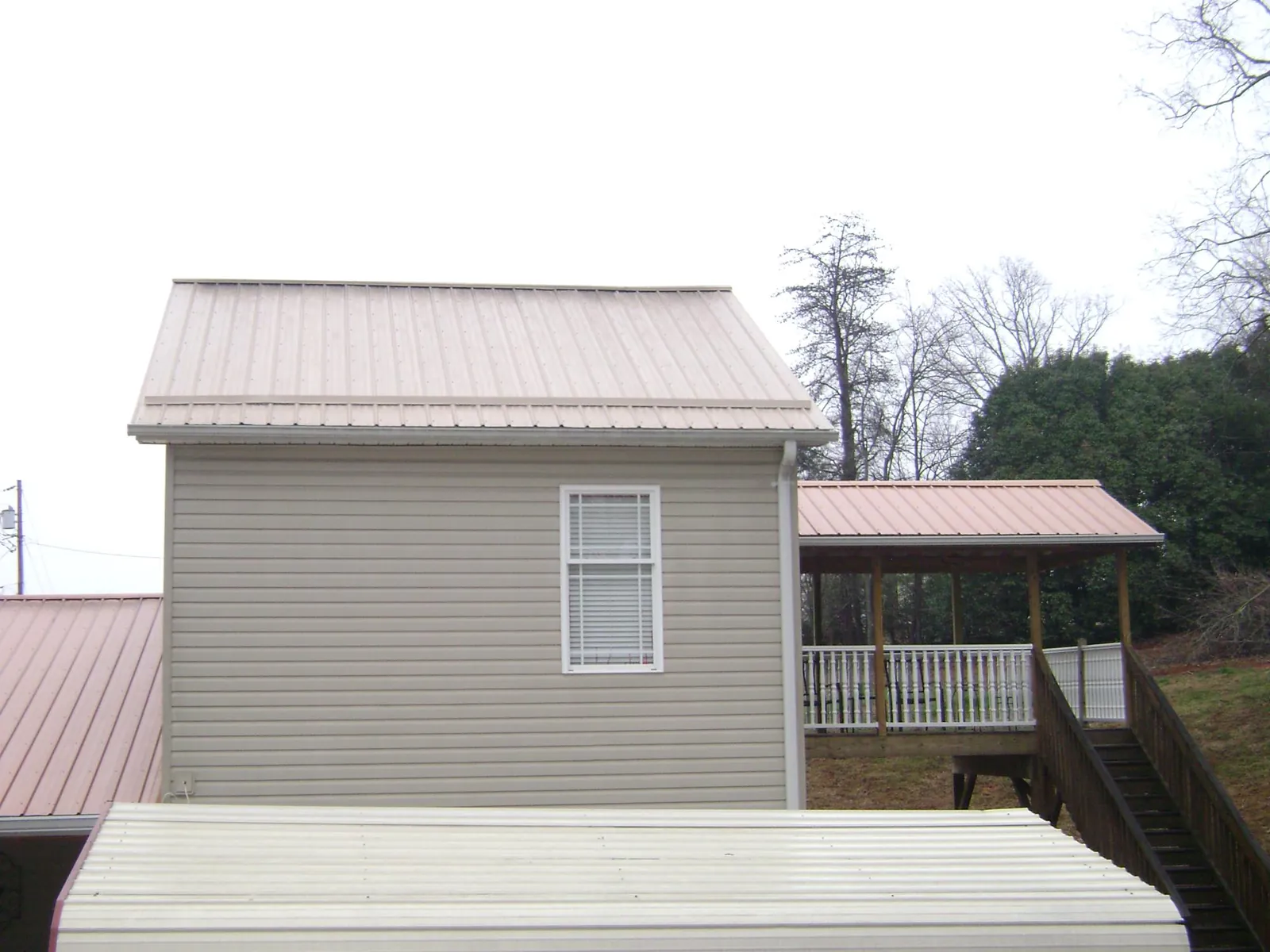 Tan metal roofs on a two story addition and attached porch, from a Roof Replacement job in Monongahela