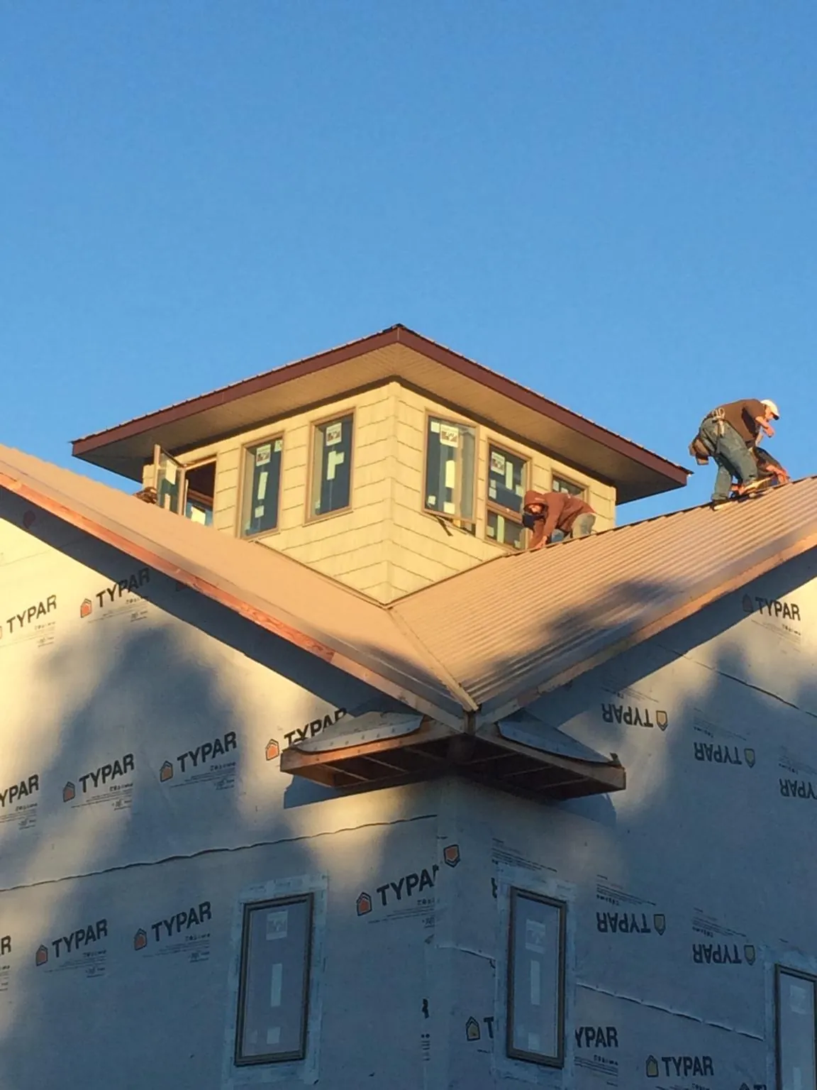 Roofers working around a rooftop cupola on a new metal roof at sunset — Roof Waterproofing in Monongahela by Roofing Brothers